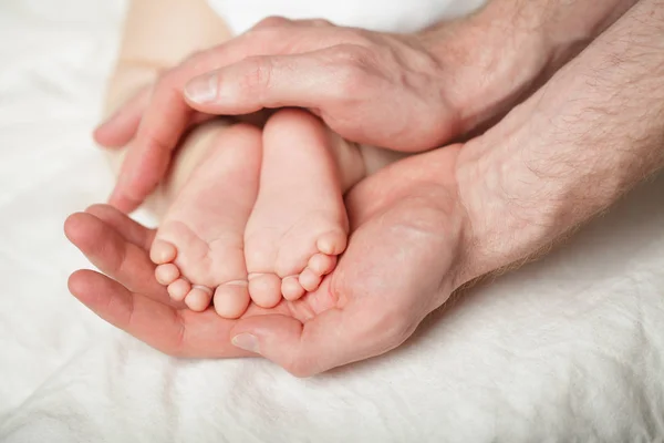 Father holding newborn babyfeets in her hands on white backgroun — Stock Photo, Image