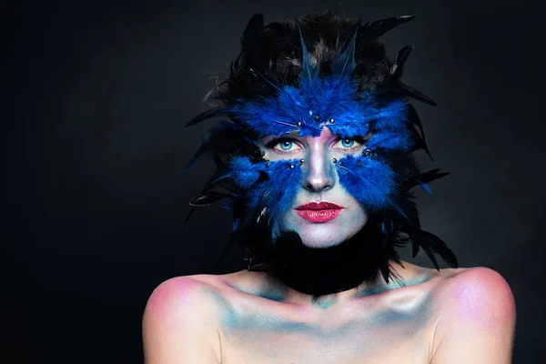 Halloween character concept. Model face with bird makeup on dark