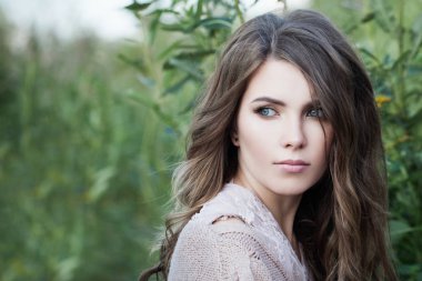 Kahverengi kıvırcık saçlı ve yeşil çim üzerinde berrak cilt ile Sevimli kadın