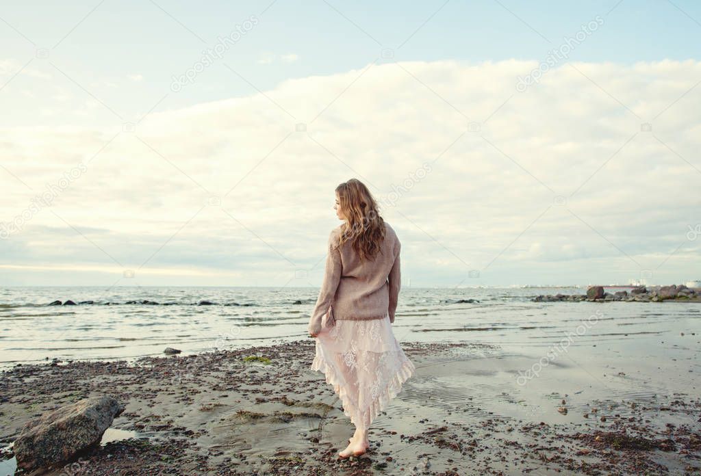 Pretty woman walking along the ocean coast