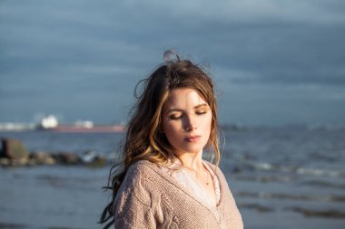 Okyanus kıyısında rahatlatıcı uzun kıvırcık saçlı Pretty kadın