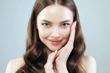 Açık tenli ve kahverengi saçlı, gülümseyen genç bir kadın. Cilt bakımı