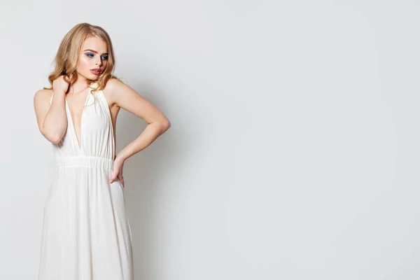 Mujer bonita con vestido de noche blanco contra la pared blanca — Foto de Stock