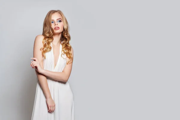 Blond kvinna i vit klänning poserar på vit bakgrund — Stockfoto