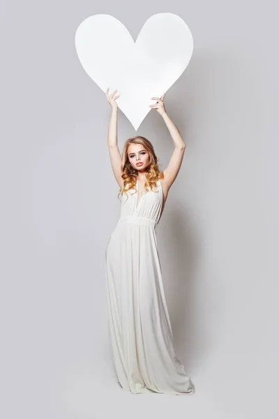 Jolie femme debout et tenant blanc vide carte de conseil d'administration — Photo