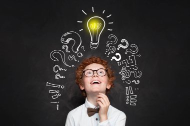 Mutlu çocuk tahta arka plan üzerinde ampul bakıyor. 