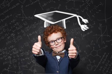 Mezuniyet şapkasında gülümseyen çocuk başparmak gösteren