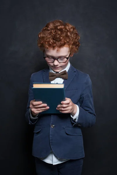 Bambino con libro su sfondo lavagna — Foto Stock