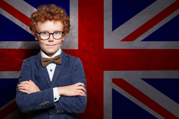 Smart child in suit and glasses on the UK flag background.