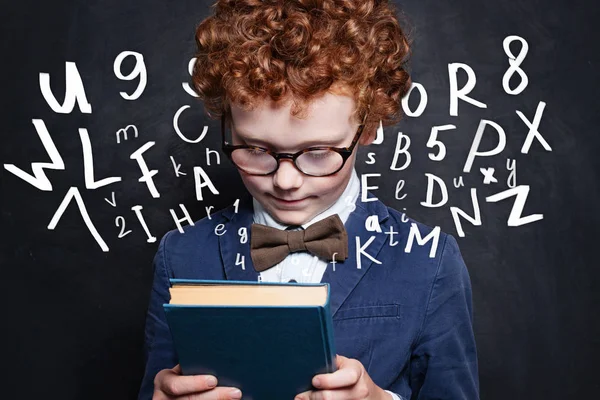 Kind Holding boek met letters tegen schoolbord achtergrond — Stockfoto