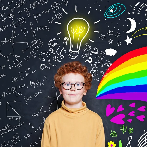 Симпатичный умный мальчик на фоне школьной доски с идеей лампочки . — стоковое фото