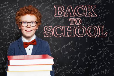 Mutlu yakışıklı çocuk gülümseyen ve tebeşir üzerinde kitap tutan 