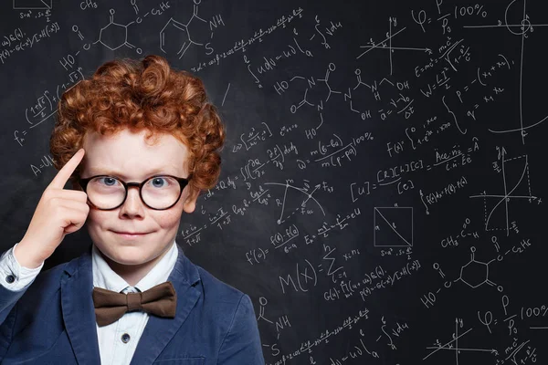 黒板の背景に教室で面白い赤毛スマートな子供の少年 — ストック写真