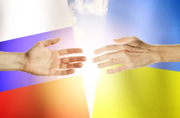 Руки людей на фоне флагов России и Украины — стоковое фото