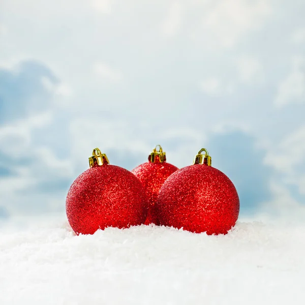 Boules de Noël rouges sur fond de neige blanche contre ciel bleu — Photo