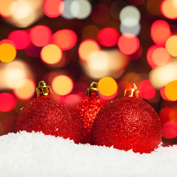 Rote Christbaumkugeln im weißen Schnee gegen abstraktes Bokeh-Licht — Stockfoto