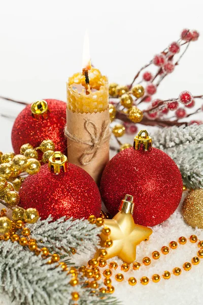 Composição de Natal com bugigangas vermelhas, guirlanda dourada, vela e fita Imagem De Stock