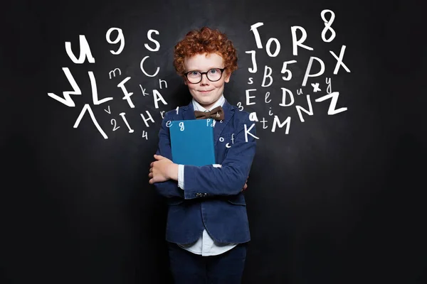 Школьник в синей студенческой форме с книгой на доске — стоковое фото