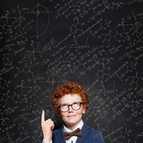 Smart child boy with curly ginger hair in glasses. 