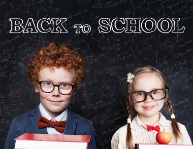 Kitap tutan ve gülümseyen gözlük takan akıllı çocuklar.