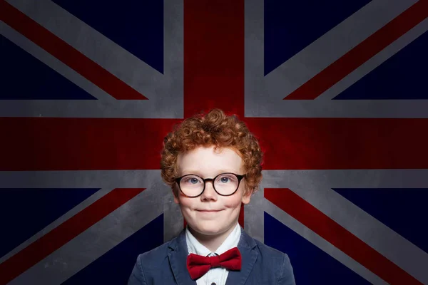 Šťastný chlapeček v brýlích s vlajkou Spojeného království. — Stock fotografie