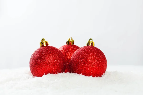 Três bugigangas vermelhas no fundo branco da neve. Composição de Natal — Fotografia de Stock