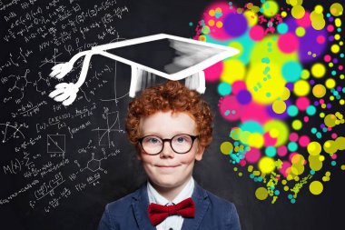 Tebeşir tahtasıüzerinde gözlük ve mezuniyet şapkası takan gülümseyen çocuk 