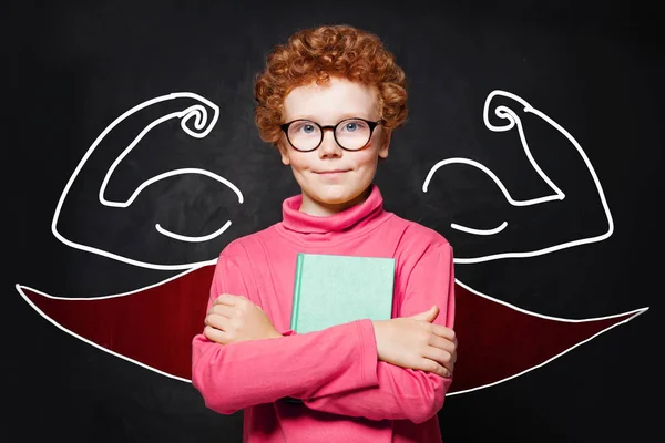 Junge im Superhelden-Outfit mit Buch in der Hand. Smart-Kids-Porträt — Stockfoto