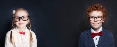 Tebeşir tahtası arka planda gülümseyen gözlük takan öğrenci çocukları. 