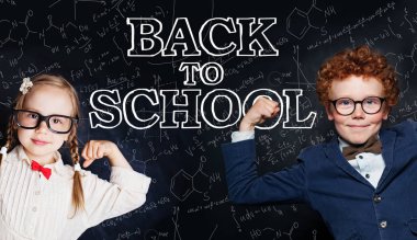 Okul üniforması mutlu akıllı çocuklar kara tahtaüzerinde eğleniyor 