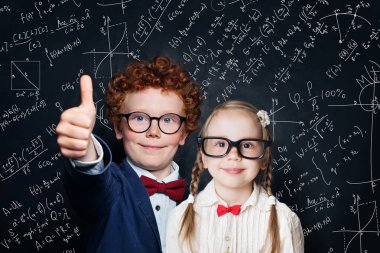 Okul üniforması içinde mutlu küçük çocuklar tahtaüzerinde eğleniyor 