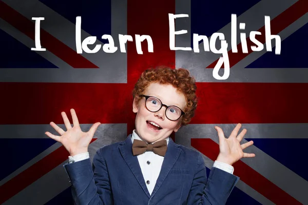 Un chico aprendiendo inglés. Joven alumno en el fondo de la bandera británica —  Fotos de Stock