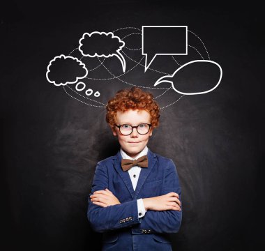 Okul karatahta arka planında boş konuşma bulutları olan kızıl saçlı çocuk.