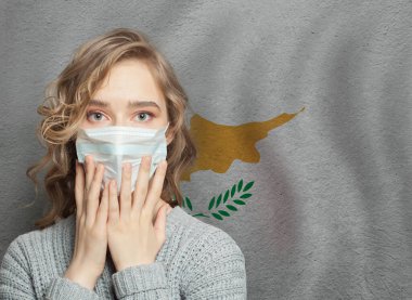 Kıbrıs bayrağı geçmişinde tıbbi maskeli korkmuş bir kadın. Kıbrıs konseptinde grip salgını ve aile içi şiddet