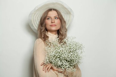 Beyaz şapkalı güzel olgun kadın elinde çiçekler, portre