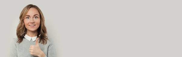 Милая женщина показывает большой палец вверх и улыбается на белом фоне баннера
