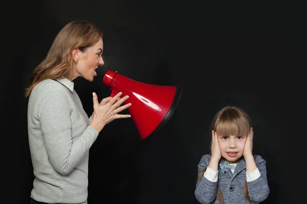 妈妈用扩音器对不幸的女儿大喊 可怜的小女孩用手捂住耳朵 家庭问题概念 — 图库照片