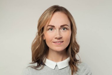 Güzel sıradan bir kadın beyaz arka planda gülümsüyor, portre