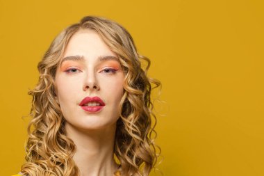Güzel kadın yüzü. Sarı arka planda uzun kıvırcık saçlı kadın model.