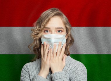 Macaristan bayrağında yüz maskesi takan paniklemiş bir kadın. Grip salgını ve virüs koruma kavramı