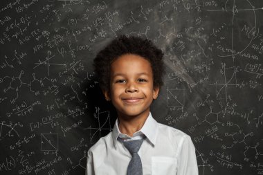 Kara tahtada bilim ve matematik formülleri olan mutlu siyah çocuk öğrenci.