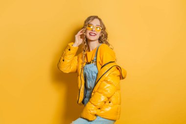 Parlak arka planda sarı kışlık ceketli mutlu model kadın.