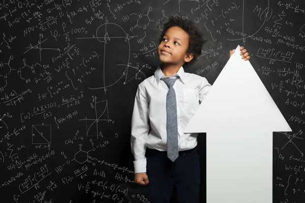 聪明的黑人学生男孩拿着白色空白旗箭头在黑板上背景与科学公式 — 图库照片