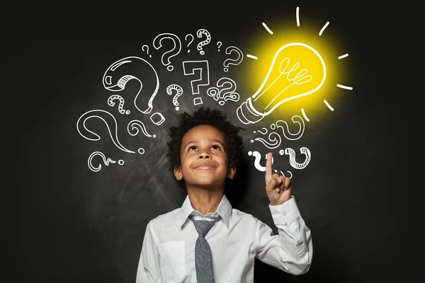 電球で黒の背景に賢い小さな男の子 ブレーンストーミングとアイデアのコンセプト — ストック写真