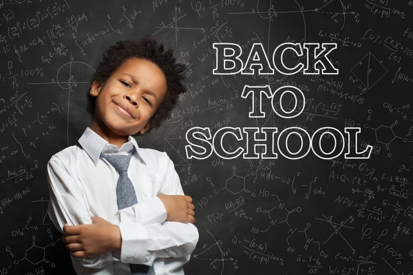 Proud black child student on blackboard background. Back to school concept