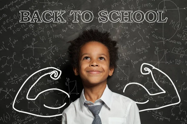 Child smart student in classroom on chalkboard background. Back to school concept