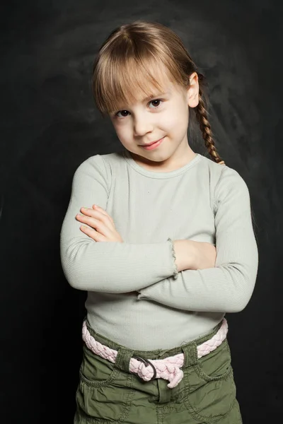 幸せな子供の女の子笑顔と立っている腕交差上の黒板の背景 — ストック写真