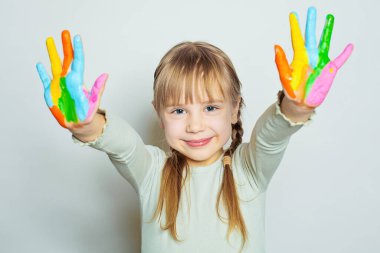 Beyaz arka planda renkli elleri olan sevimli bir kız çocuğu.