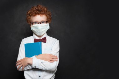 Tahta arka planda tıbbi koruyucu yüz maskesi takan zeki çocuk.