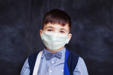 Siyah arka planda tıbbi koruyucu yüz maskesi takan küçük çocuk.